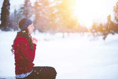 女人坐着闭着眼睛被雪包围
